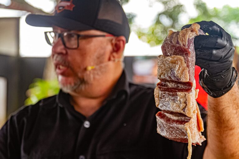 Quem aprecia um bom churrasco sabe que a carne de sol é um dos tesouros da culinária brasileira. No entanto, o preparo tradicional exige planejamento: horas de molho para retirar o excesso de sal, troca de água e o risco constante de o prato passar do ponto. É contra essa burocracia na cozinha que a marca "Traz que Eu Asso" vem ganhando destaque, apresentando uma versão gourmet do produto que promete — e entrega — praticidade absoluta: ela vai direto da embalagem para o fogo. O segredo por trás dessa inovação é uma técnica de salga e maturação equilibrada, desenvolvida pelo especialista em charcutaria Kerley Freitas. Natural de Quixadá (CE), Kerley uniu o conhecimento centenário do sertão com formações modernas em cursos de American BBQ, Dry Age e defumação para criar um produto único. Adeus ao Dessalgue Diferente da carne seca ou do charque, que possuem altas concentrações de sal para conservação prolongada, a carne de sol da "Traz que Eu Asso" é tratada como um corte de alta gastronomia. "Nossa técnica permite que a carne já esteja pronta para assar. Ela não precisa passar por nenhum processo prévio. É colocar na chapa, na churrasqueira ou até na Air Fryer", explica Kerley. O resultado é uma carne que mantém a umidade interna, as fibras macias e um sabor que não é mascarado pelo sal, mas sim realçado por ele. Cortes Nobres na Tábua A inovação não para no processo de maturação. A marca elevou o status da carne de sol ao aplicá-la em cortes tradicionalmente nobres. O que antes era restrito ao "coxão duro" ou "alcatra", agora ganha versões em: ● Picanha ● Ribeye (Ancho) ● Chorizo ● Maminha ● Carneiro Essa seleção transforma o churrasco de final de semana em uma verdadeira experiência de Steakhouse, mas com a alma e o tempero do Nordeste brasileiro. Ciência Gastronômica Kerley faz questão de desmistificar o produto para os consumidores. "Existe muita confusão entre carne de sol, carne seca e charque. A diferença está na ciência: na quantidade de sal aplicada e na porcentagem de líquidos que permanecem na carne. Nós trabalhamos para manter o equilíbrio que garante a suculência, algo que a salga pesada costuma retirar", pontua o especialista. O rigor técnico é tamanho que o produto não conquistou apenas o paladar brasileiro; hoje, a técnica é replicada em solo americano, com certificação internacional, garantindo que a tradição nordestina seja servida com padrão de excelência em qualquer lugar do mundo. Seja para o churrasqueiro profissional ou para quem mora em apartamento e usa a praticidade da frigideira, a "Traz que Eu Asso" prova que é possível unir a tradição de 100 anos com a agilidade que o tempo moderno exige. ________________________________________ Box Informativo: Você sabe a diferença? ● Carne de Sol: Levemente salgada e maturada em ambiente controlado. Mantém a umidade e maciez. (Foco da Tras que Eu Asso). ● Carne Seca: Recebe uma carga maior de sal e é exposta ao sol por mais tempo, perdendo muita umidade. Precisa obrigatoriamente de dessalgue. ● Charque: Processo mais intenso de salga e secagem, com maior durabilidade, mas textura muito mais firme e salgada.