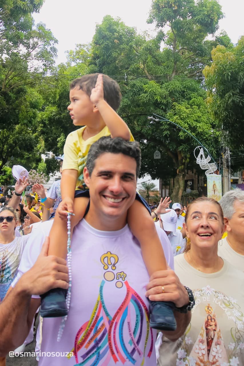 Homem com uma criança nos ombros entre romeiros durante o Círio